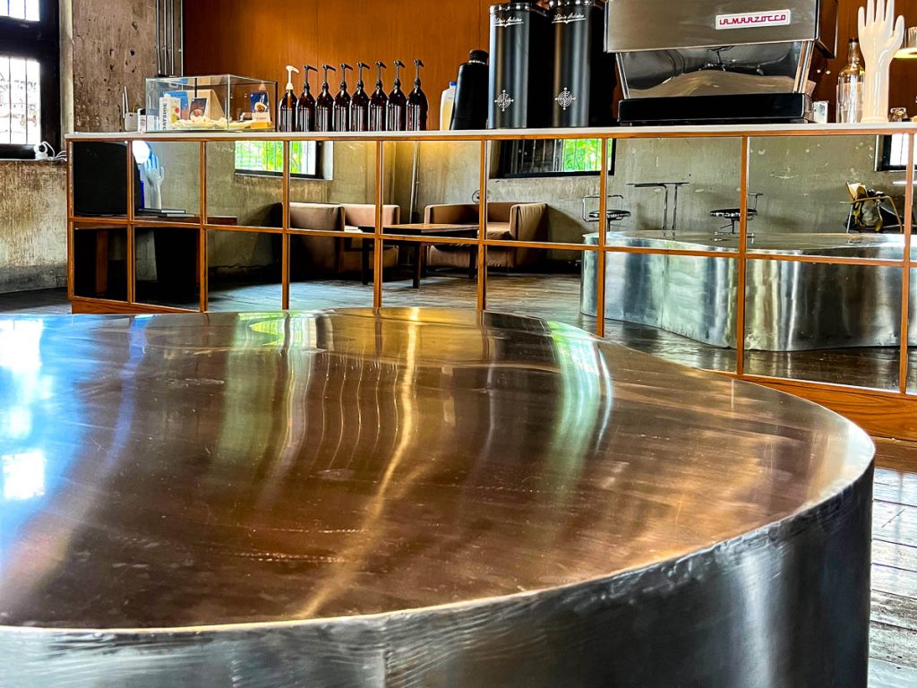 A sculptural curved stainless steel bench adds a bold, futuristic edge to Building A’s industrial-chic interior