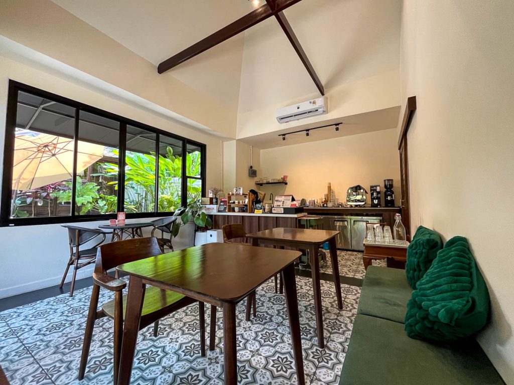 Indoor seating at Goodneighbor Cafe Chiang Mai with wooden tables, green bench seating and bright minimalist interior