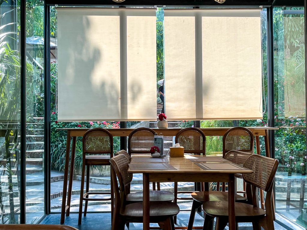 Inside Fleur Cafe: Rattan chairs, garden views, and sunlight that does half the decorating—indoor dining that still feels outdoorsy
