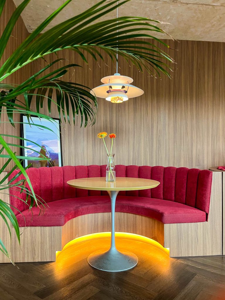Plush red velvet booths create cosy corners beneath chic pendant lamps