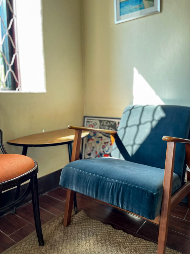 A vintage chair bathed in sunlight from a lattice window in The Pantry at Baan 104