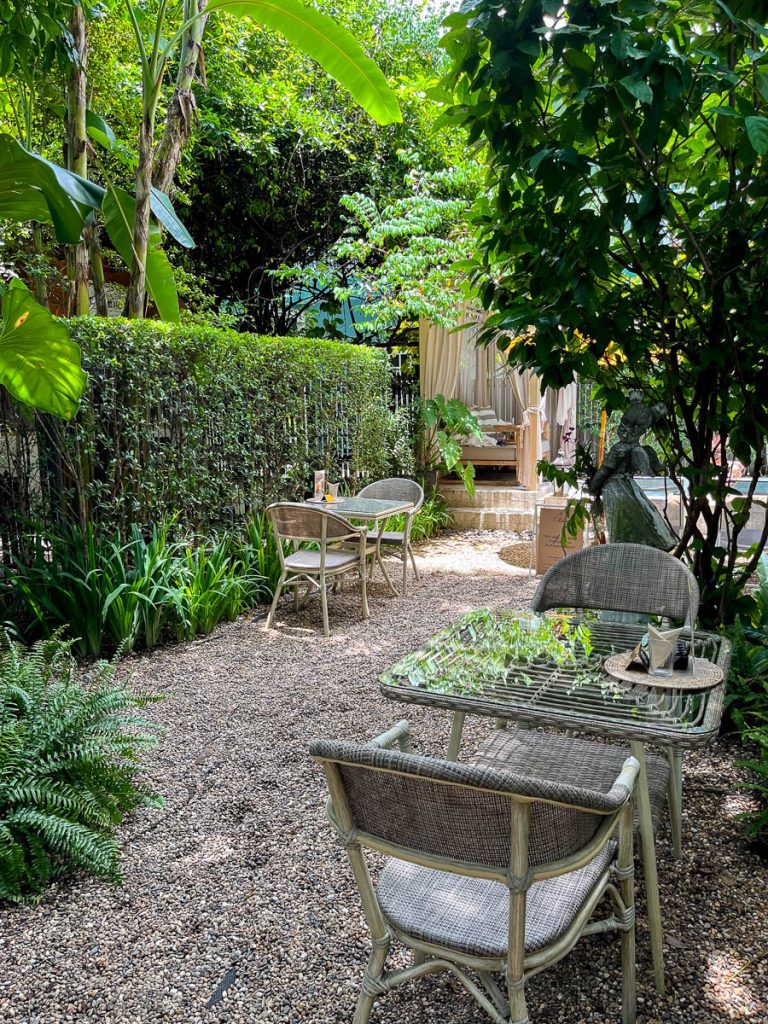 Woven chairs, dappled light, and a hush of greenery — the perfect pause from the moat’s bustle