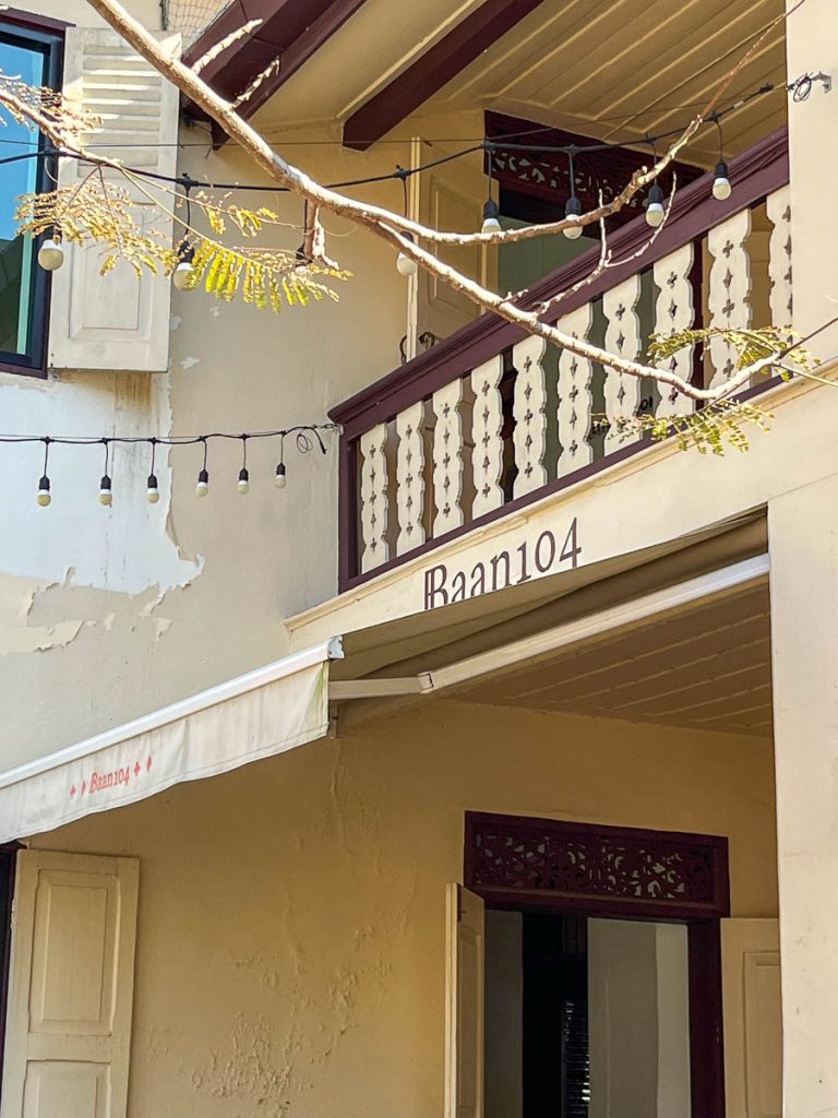 Close-up of Baan 104’s gently weathered exterior, showing the balcony, awning, and painted signage of the cafe in Chiang Mai