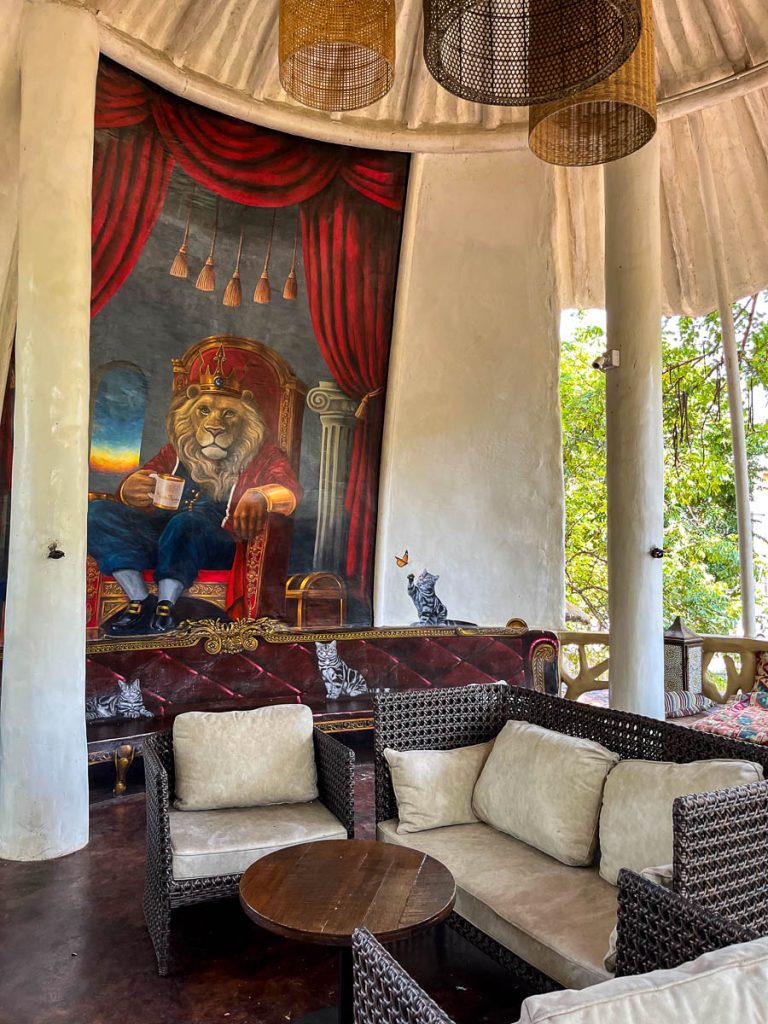 Open-air upper level of Much Room Cafe Chiang Mai with wicker seating and lion mural