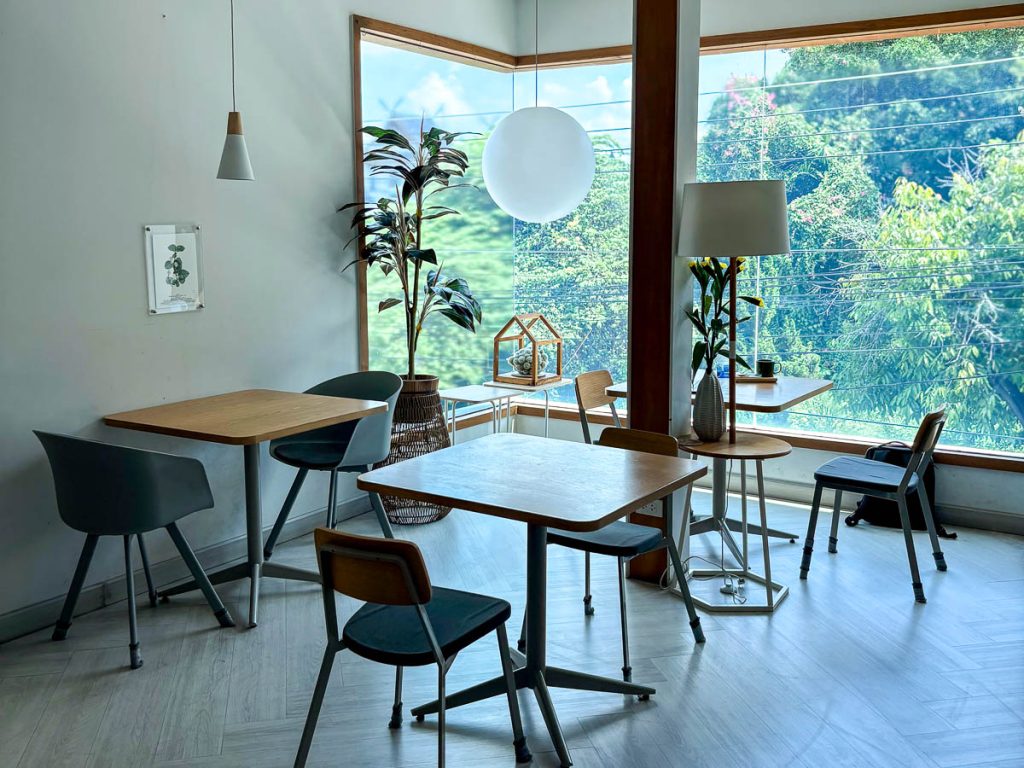 Upstairs seating area by large corner windows at Chapter One cafe in Chiang Mai
