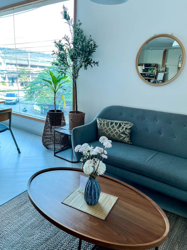 Upstairs sofa seating at Chapter One cafe in Chiang Mai with mid-century style furniture and large corner windows