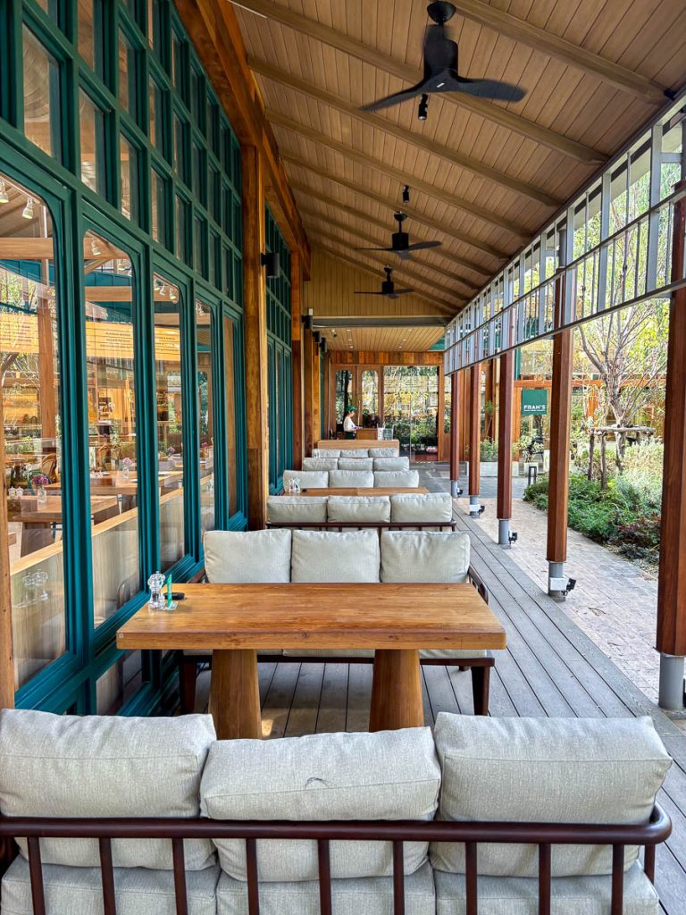 Outdoor decking at Fran’s Chiang Mai with deep green window frames and wooden sofa seating