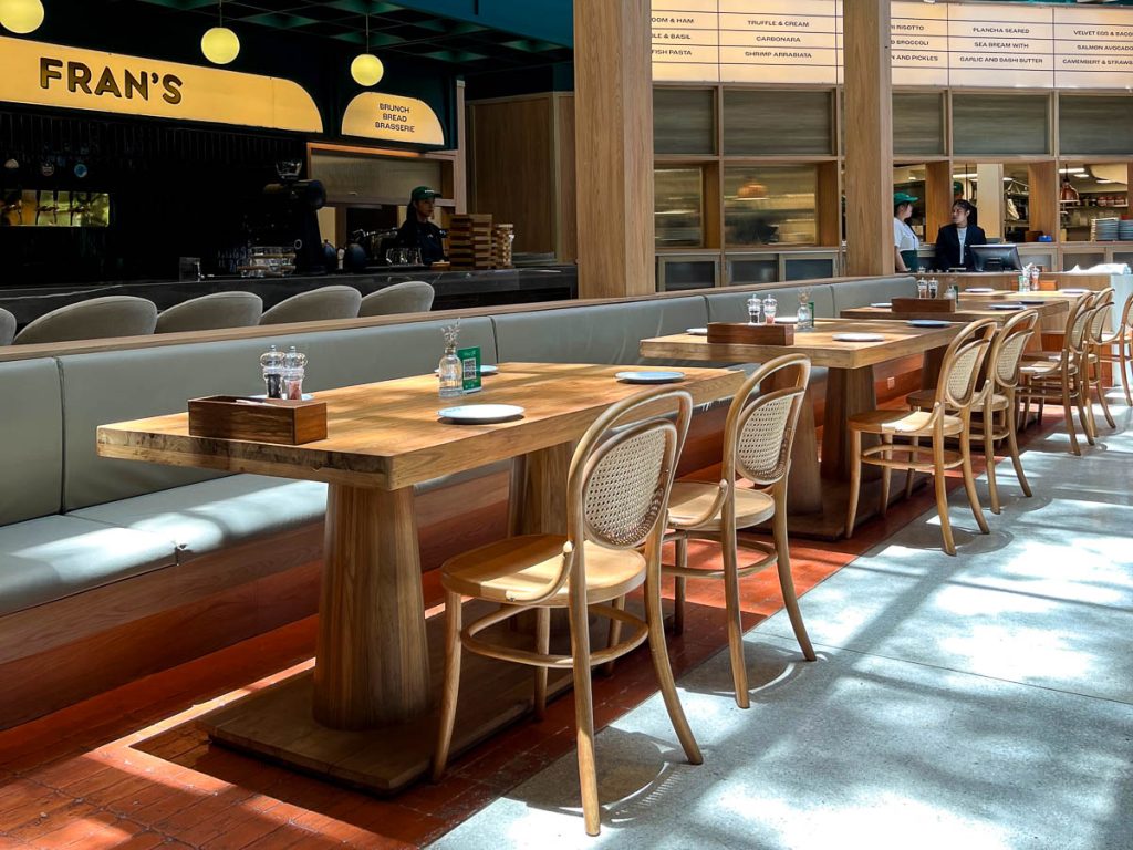 Bright indoor dining space with wooden tables and banquette seating at FRAN’S Chiang Mai, ideal for brunch dates and special occasion lunches