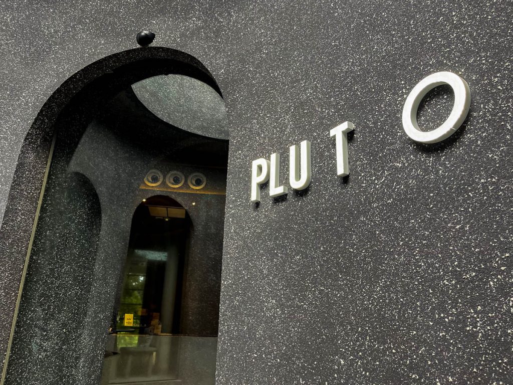 PLUTO Cafe Chiang Mai curved doorway with textured concrete facade and futuristic design