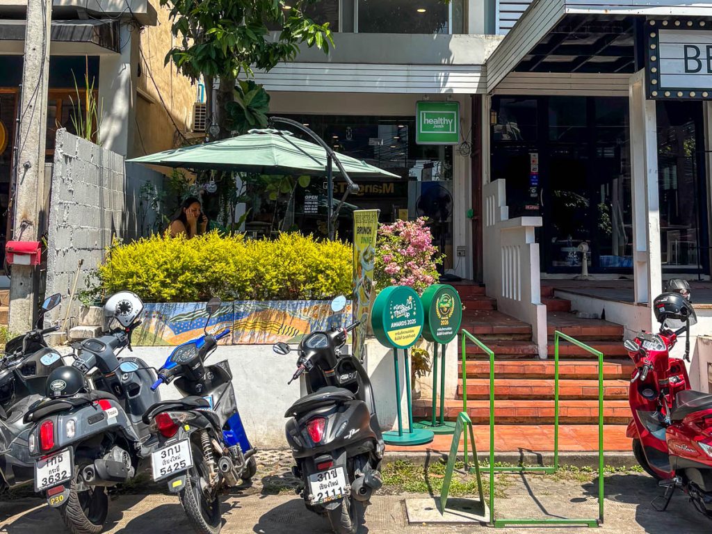 Exterior of Healthy Junk in Nimman, Chiang Mai, with outdoor terrace seating and green branding