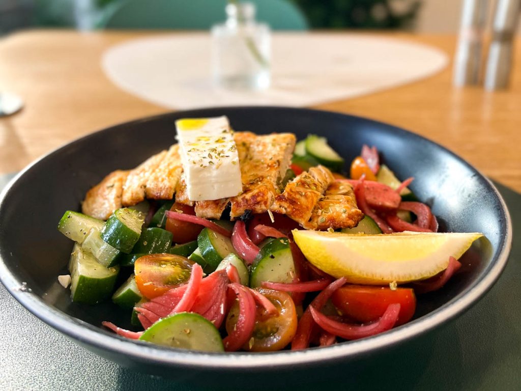 Healthy Junk Greek salad with chicken, tomatoes, cucumber and pickled onion