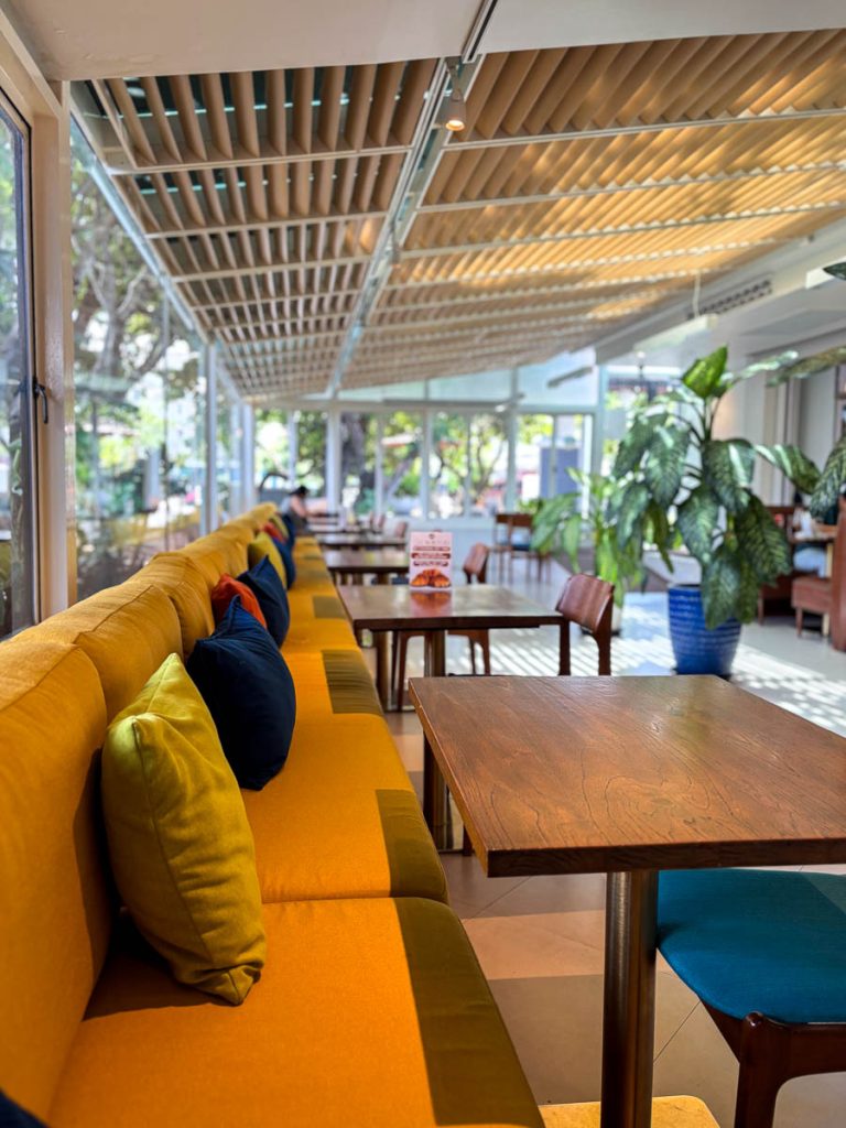 Main dining room at Food4Thought East with yellow banquette seating and slatted ceiling, Chiang Mai